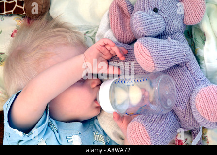Eine acht - Monate altes Baby Boy schläft in seinem Bettchen mit seiner Flasche noch in den Mund. Stockfoto