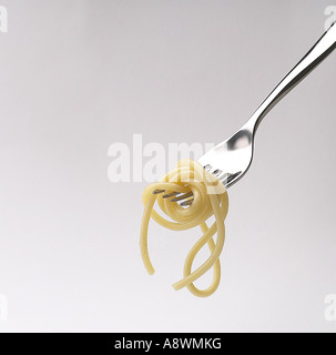 FRISCHE SPAGHETTI AUF EINER GABEL AUF WEIßEM HINTERGRUND Stockfoto