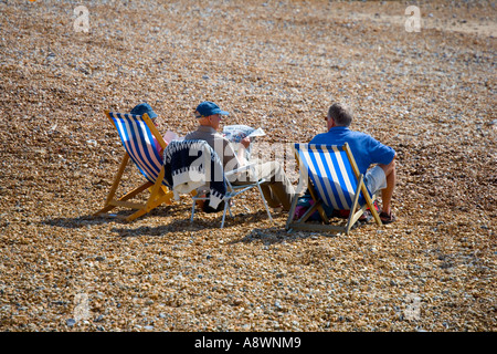 Drei ältere Menschen sitzen am Strand von Easbourne, Sussex, England, UK Stockfoto