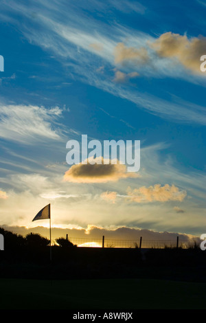 Das letzte Loch des Tages. Die Flagge am 18. Loch flattert im Wind, während die Sonne untergeht. Stockfoto