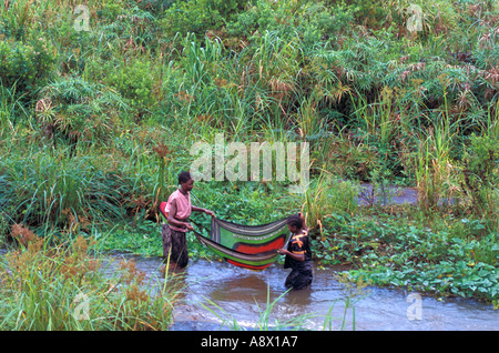 Afrika Kenia Malindi Kenia Mutter und Tochter verwenden Sie ein traditionelles Kanga Tuch wie ein Netz, Fische im Fluss zu erfassen Stockfoto