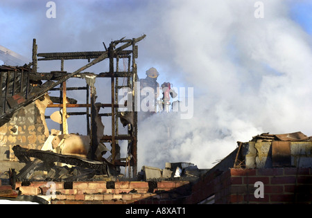 Ein Feuerwehrmann ist durch Rauch erblickt, während ein Haus Feuer UK Außerbetriebnahme Stockfoto