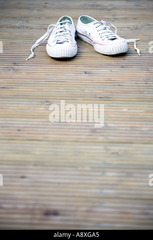 ALTE TURNSCHUHE AUF GARTEN DECKING LIEGEND Stockfoto