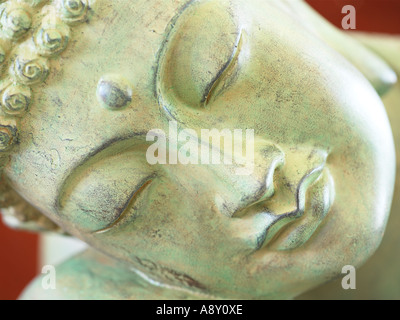 Nahaufnahme von einer Buddhastatue Gesicht vor rotem Hintergrund Stockfoto