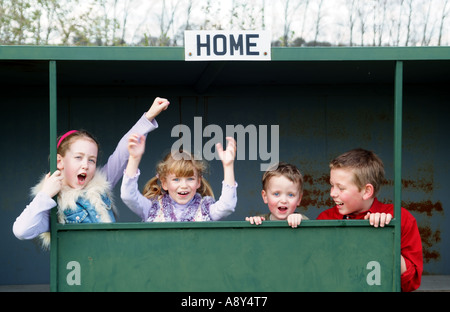 Vier junge Sport-Fans auf der Trainerbank jubeln ihre Fußballmannschaft Stockfoto