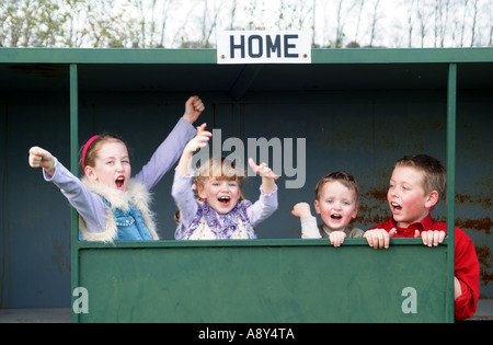 Vier junge sport Fans auf der Trainerbank jubeln ihre Fußballmannschaft Stockfoto