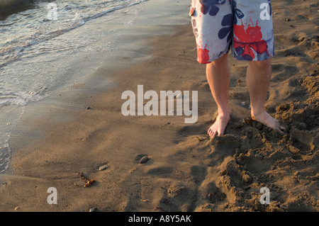 Detail von den Beinen und Füßen eines jungen Mannes Stand am Sandstrand Stockfoto