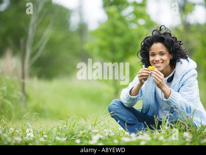 Junge Frau sitzt auf dem Rasen mit Blumen Stockfoto