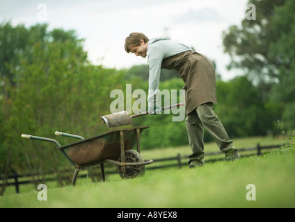 Mann, die Schaufeln Schmutz in Schubkarre Stockfoto