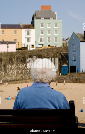 Rückansicht von hinten eine alte Frau Dame graue Haare allein sitzen auf Bank Blick auf Strand Tenby Süd-west Wales UK Stockfoto