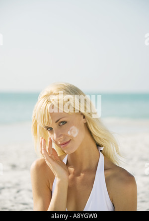 Frau, die Anwendung von Sonnenschutzmitteln, um am Strand zu stellen Stockfoto
