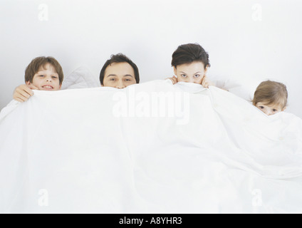 Familie im Bett Abdeckungen unter Nase hochziehen Stockfoto