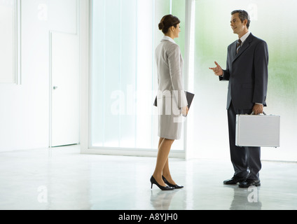 Geschäftsmann und Geschäftsfrau in Lobby sprechen Stockfoto