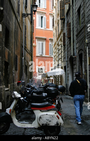 Mann in Seitenstraße in Italien gesäumt von Roller Stockfoto
