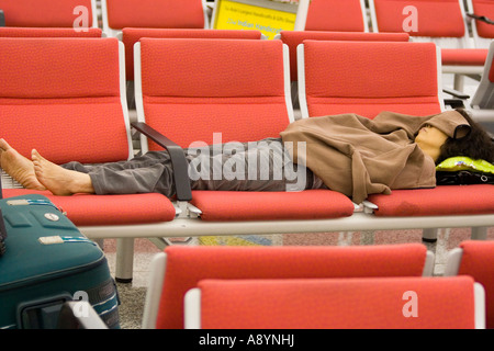 Frau Reisenden schlafen über Nacht auf Stühlen Hong Kong International Airport-HKG Stockfoto