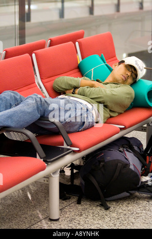 Mann-Reisenden schlafen über Nacht auf Stühlen Hong Kong International Airport-HKG Stockfoto