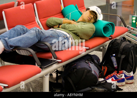 Mann-Reisenden schlafen über Nacht auf Stühlen Hong Kong International Airport-HKG Stockfoto