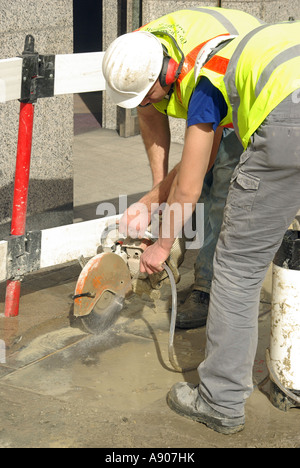 Bürgersteig Reparatur Vermittlung In Arbeit zwei Arbeiter mit Scheibenfräser & Spritzwasser um zu dämpfen Kontrolle & Staub Stockfoto