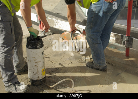 Strang London Pflaster Reparatur Relays In Arbeit zwei Arbeiter mit Scheibenfräser & Wasser sprühen, um Kontrolle Staub dämpfen Stockfoto