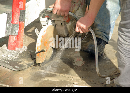 Bürgersteig Reparatur Vermittlung In Arbeit zwei Arbeiter mit Scheibenfräser & Spritzwasser um zu dämpfen Kontrolle & Staub Stockfoto