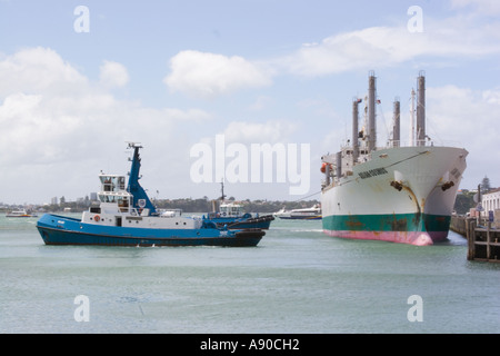 Auckland harbour New Zealand Frachtschiff wird eingespannt aus Dock von Schlepper Stockfoto