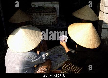 Farbfoto von Frauen, die Karten mit traditionellen Strohhüten spielen, Hoi-an, Vietnam, Asien Stockfoto