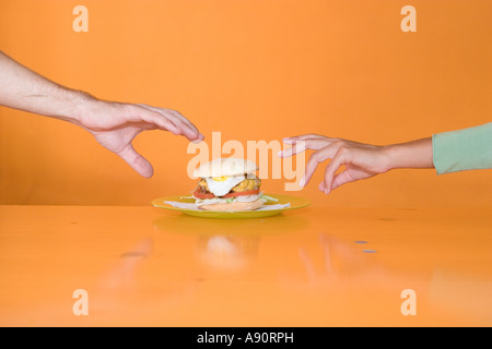 Zwei Hände, um Hamburger zu erreichen Stockfoto