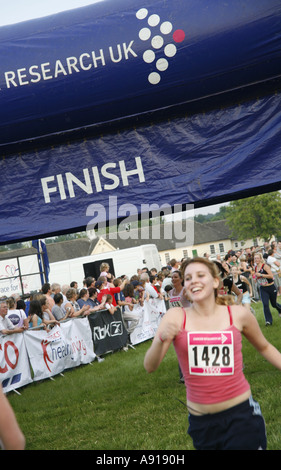 Frau Läufer sprinten über die Ziellinie beim Race For Life Charity Event Stockfoto