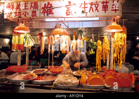 Ein Mann arbeitet auf einem Nachtmarkt, Verkauf von Fleisch und Fisch in Hong Kong. Stockfoto