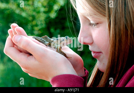 Lernen über die Tierwelt hautnah wie ein Schulmädchen sanft hält einen Frosch Stockfoto