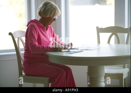 Ältere Frau zahlt Rechnungen Stockfoto