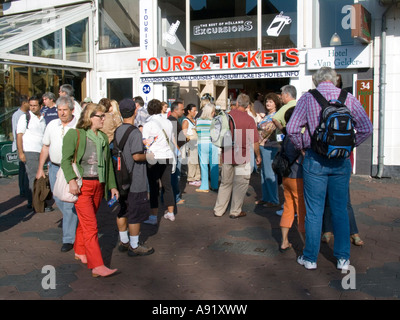 Touristen und Besucher warten außerhalb Kasse beizutreten täglich Busreisen Damrak Amsterdam Niederlande Stockfoto