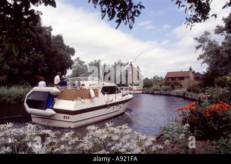 Englisch Norfolk Broads Motorboot in Hunsett Mill Windmühle & Ferienhaus am Flussufer Haus Sommergarten Blumen in Stalham River Ant East Anglia England Großbritannien Stockfoto