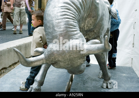 Arles, Frankreich, Feria 'Stierkampffest' französisches Kind posiert für Kamera mit Bullskulptur 'Galerie Ausstellung' Metallobjekt Stockfoto