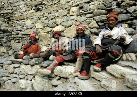 Vier freundliche Mann in traditioneller Kleidung gemacht der Wolle sitzen an einer Wand Phu Nar-Phu Annapurna Region Nepal Stockfoto