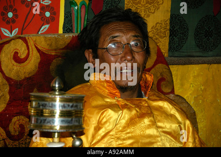 Porträt-Mönch Lama Sonom gekleidet in einen gelben Umhang mit Brille drehen eine Gebetsmühle im Kloster Tashi Gompa Phu Nar-Phu Stockfoto