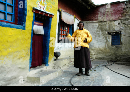 Mönch Lama Sonom gekleidet in einen gelben Umhang drehen eine Gebetsmühle vor Kloster Tashi Gompa Phu Nar-Phu Annapurna Region Stockfoto