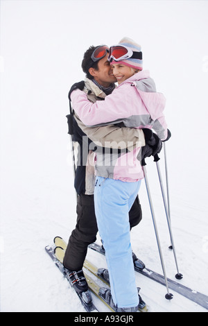 Paar, umarmen, stehend auf Skiern auf Skipiste Stockfoto