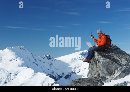 Bergsteiger mit Laptop mit Walkie-talkie auf Berggipfel Stockfoto