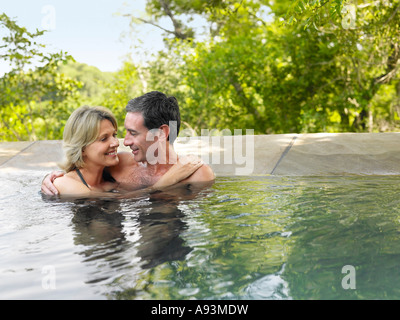 Erwachsenes paar umarmt im Pool, Lächeln Stockfoto
