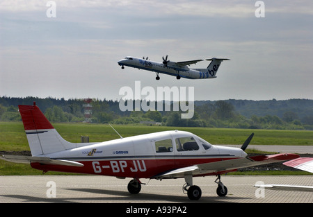Flybe Flugzeug abheben aus Southampton Airport und Leichtflugzeugen warten auf der Piste. Stockfoto