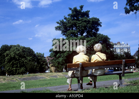 Ältere oder alte oder im Ruhestand in gelbe Blusen auf einer Bank in Clapham Common South London UK Stockfoto