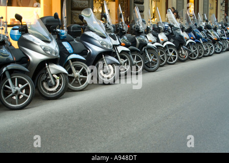 Horizontale hautnah aus einer Reihe von vielen Mopeds und Motorroller geparkt am Straßenrand in Florenz. Stockfoto