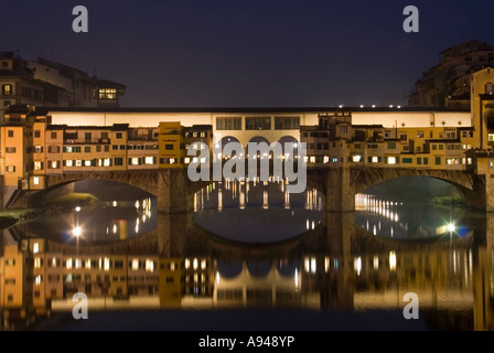 Horizontale Nahaufnahme von der Ponte Vecchio [alte Brücke] beleuchtet in der Nacht spiegelt sich in den Fluss Arno. Stockfoto