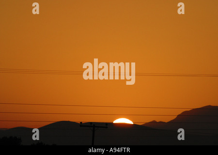 Telegrafenmasten Kabel in den Sonnenuntergang mit Bergen im Hintergrund Stockfoto