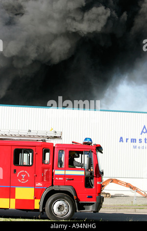 vertikale Feuerwehrauto durch die Seite der Straße neben Rauch aufsteigt aus industriellen Feuer bei medizinischen Lager Coleraine geparkt Stockfoto