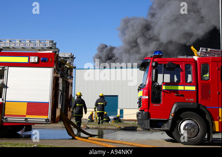 Feuerwehrfahrzeuge mit Schläuchen verbunden unter Rauchsäule am Feuer bei medizinischen Lager coleraine Stockfoto