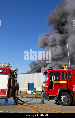 Feuerwehrfahrzeuge mit Schläuchen verbunden unter Rauchsäule am Feuer bei medizinischen Lager Coleraine vertikale Stockfoto