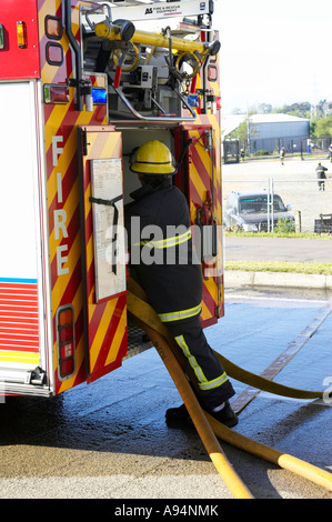 Feuerwehrmann legt Schläuche mit Rückseite Feuerwehrauto bei Brand an medizinischen Lager coleraine Stockfoto