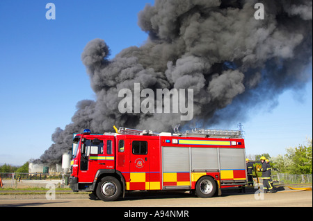 Feuerwehrauto und Crew unter riesigen Spalte mit schwarzem Rauch als Feuerwehrleute bekämpfen blaze bei medizinischen Lager coleraine Stockfoto